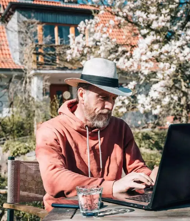 Arwed Grön von GROENIE.AI am Laptop im Garten, Webdesigner der Webseite von Fleischermeister Mehrens