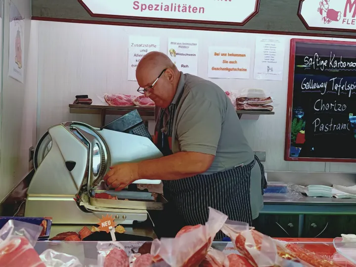 Stefan Mehrens an der Schneidemaschine im Marktwagen, Fleischermeister Stefan Mehrens